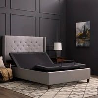 Malouf Gray adjustable bed in a bedroom setting with a tufted headboard and lamp.